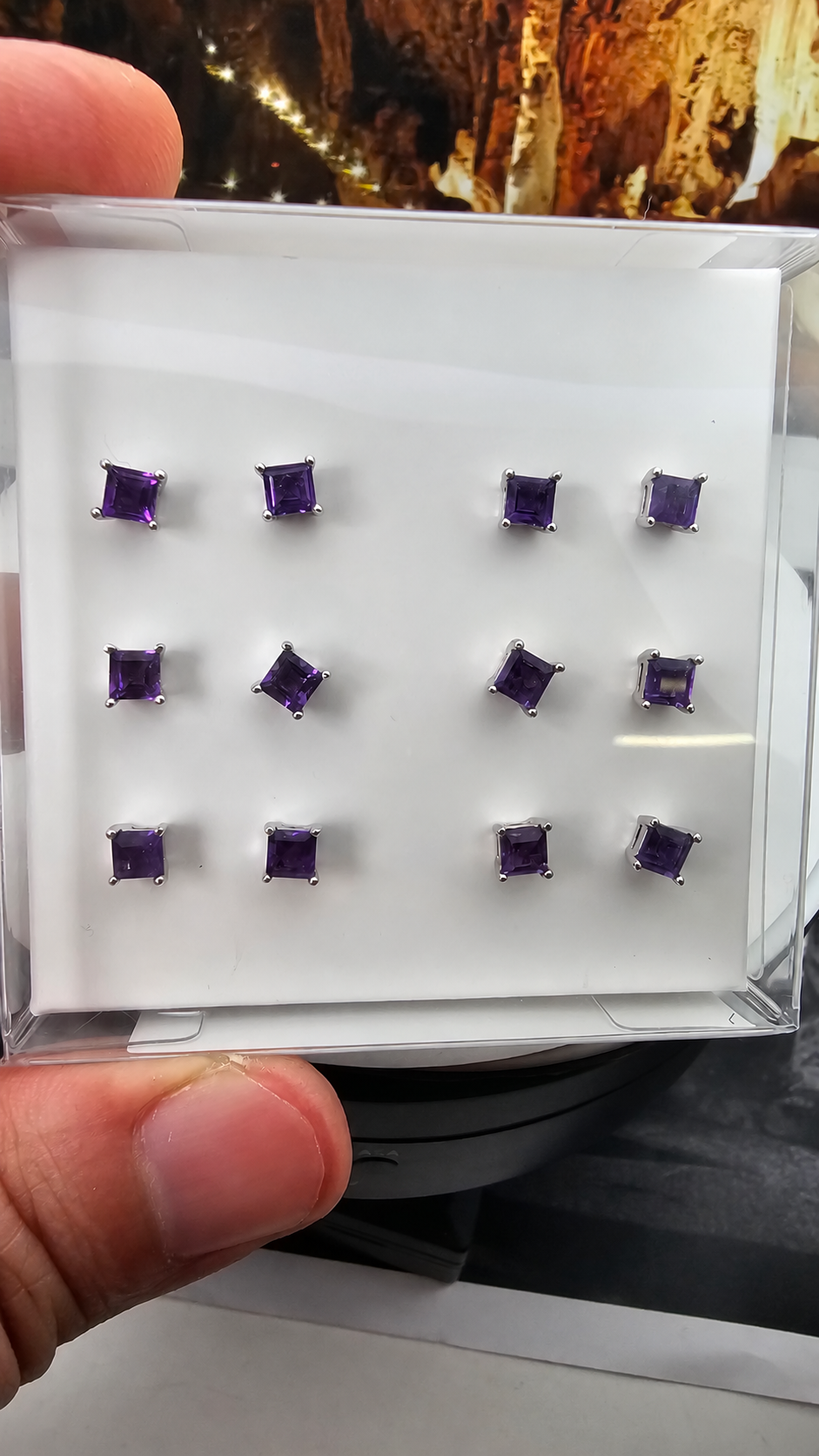 Hand-held box displaying 6 pairs of amethyst ear studs in 925 sterling silver, with handwritten label text removed. Sold per pair.