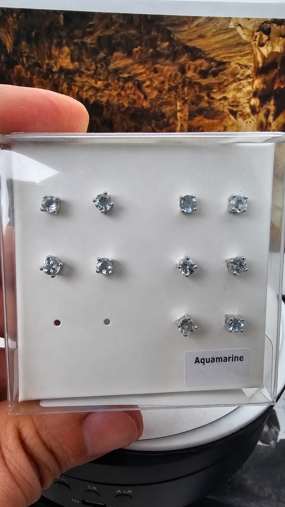 Hand-held box displaying 5 pairs of aquamarine ear studs in 925 sterling silver, with the handwritten label retouched. Sold per pair.