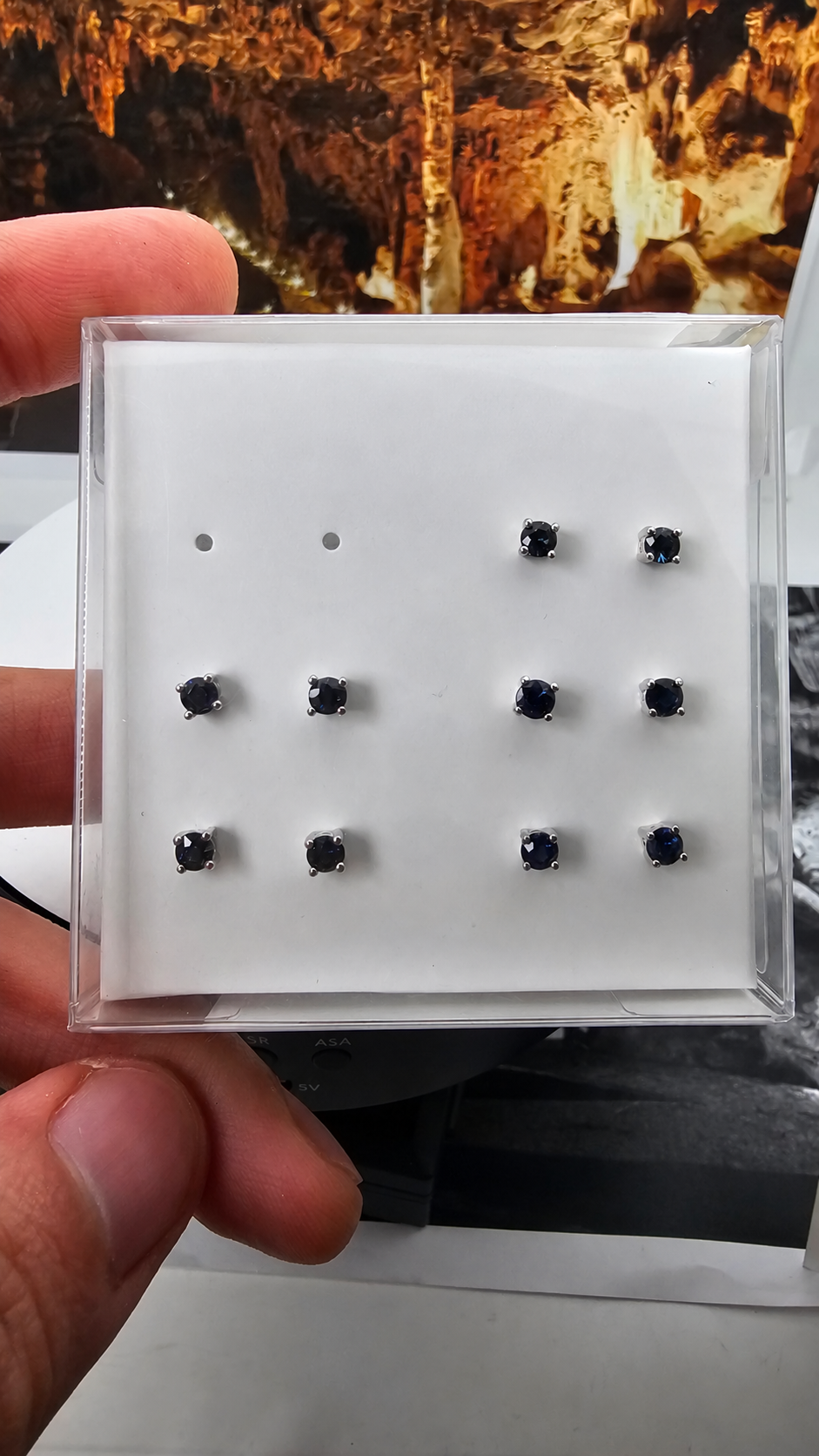Hand-held box displaying 5 pairs of blue sapphire ear studs in 925 sterling silver, with the handwritten label retouched. Sold per pair.