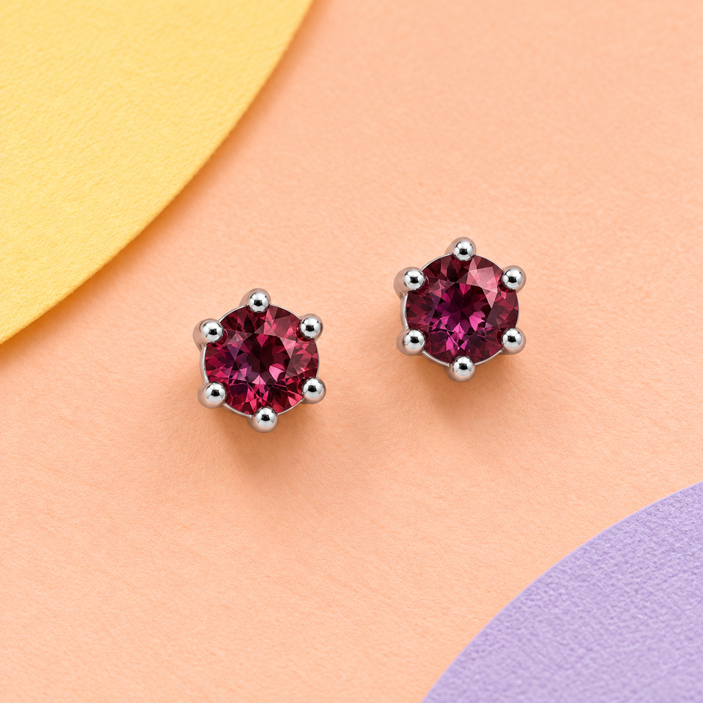 K1035: one pair of 4 mm round rubellite tourmaline studs in six-claw 925 sterling silver settings on a pastel background.